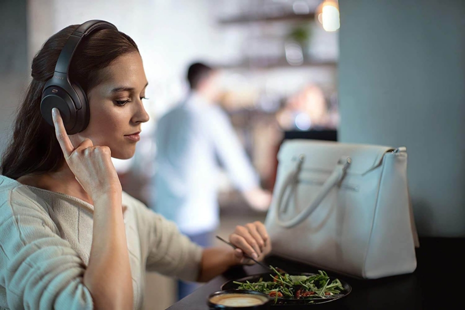 Kopfhörer: Symbolbild - Frau hört mit Kopfhörer Musik und isst Salat
