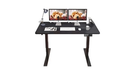 Ein höhenverstellbarer Schreibtisch in Schwarz, ausgestattet mit zwei Monitoren, Tastatur, Maus, einer Lampe und einer Tasse Kaffee vor weißem Hintergrund.