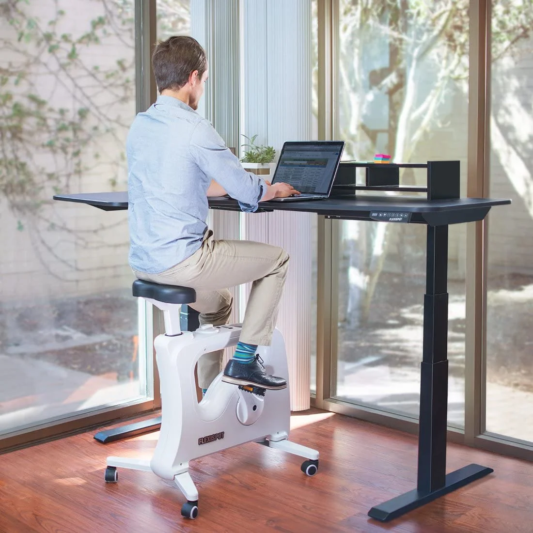 Ein Mann sitzt auf dem Flexispot V9U am Schreibtisch. Sein Rücken ist gerade, die Unterarme liegen leicht angewinkelt auf dem Tisch auf - er sitzt ergonomisch. 