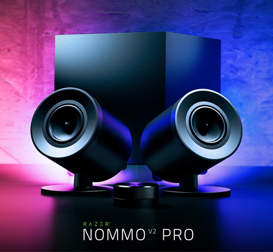 Die beiden Lautsprecher und der passende Subwoofer der Gaming-Soundanlage Razer Nommo V2 Pro vor einem in violett und rosa beleuchteten Hintergrund.